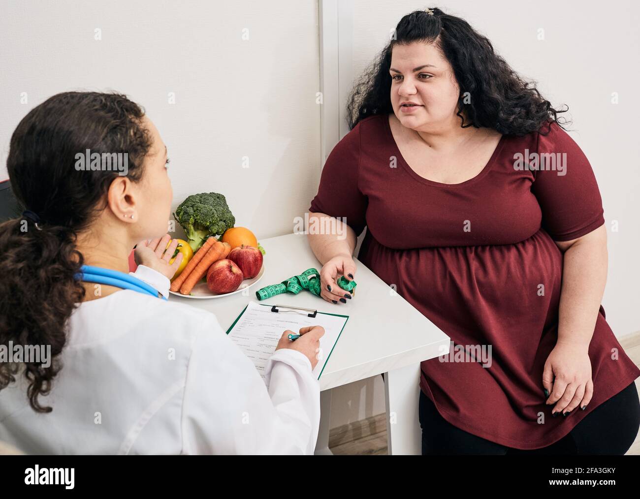 Consulenza nutrizionista. Il dietologo pianifica il programma del pasto per una paziente di peso eccessivo femminile Foto Stock