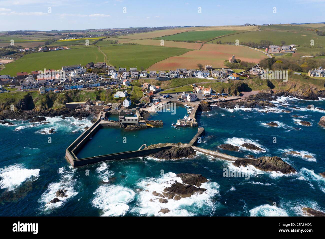 La vista aerea mostra una nave da pesca che ritorna al porto di St Abbs sulla costa del Berwickshire, Scozia, Regno Unito. Foto Stock