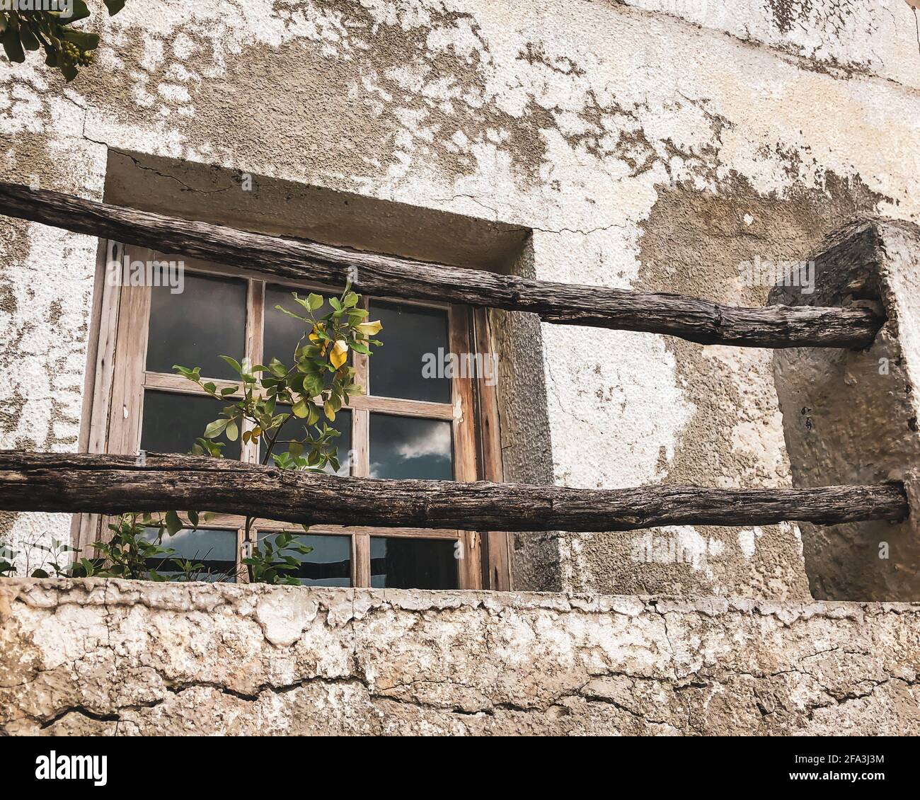 Vecchia finestra incorniciata in legno con travi in legno di fronte e. circondato da intonaco fessurato Foto Stock