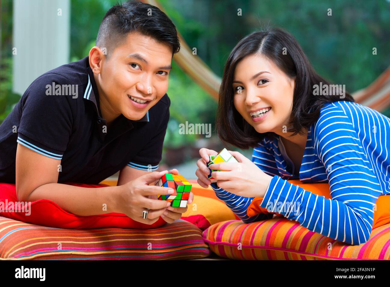 Giovane coppia indonesiana - uomo e donna - a casa giocare con un cubo magico Foto Stock