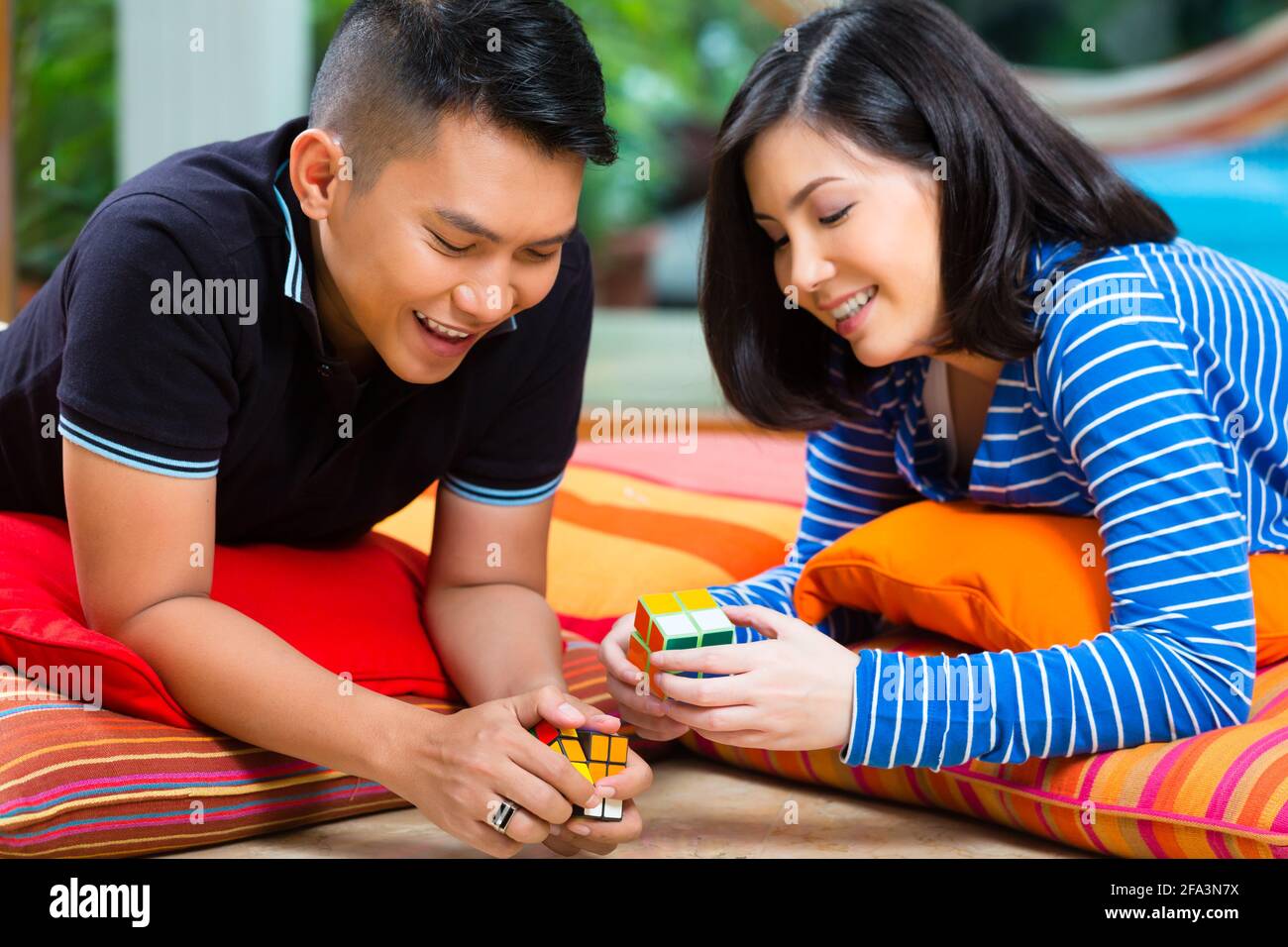 Giovane coppia indonesiana - uomo e donna - a casa giocare con un cubo magico Foto Stock