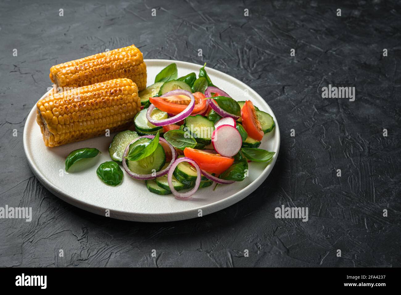 salai vegetale e mais fritto in un piatto piatto su fondo nero. Vista laterale, spazio di copia. Cibo dietetico. Foto Stock