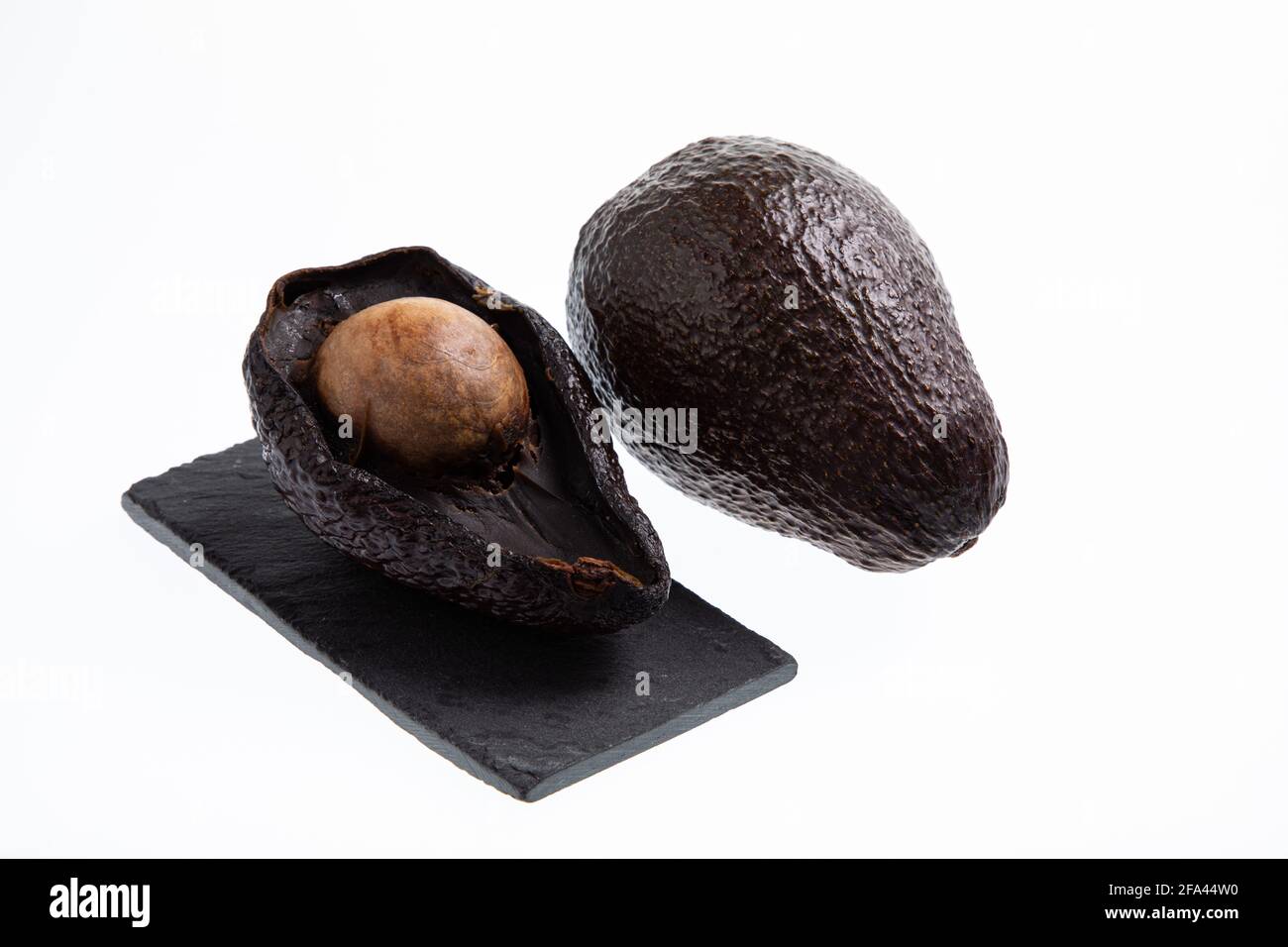 Avocado fresco e maturo accanto all'avocado marcio tagliato in metà con seme visibile isolato su bianco Foto Stock