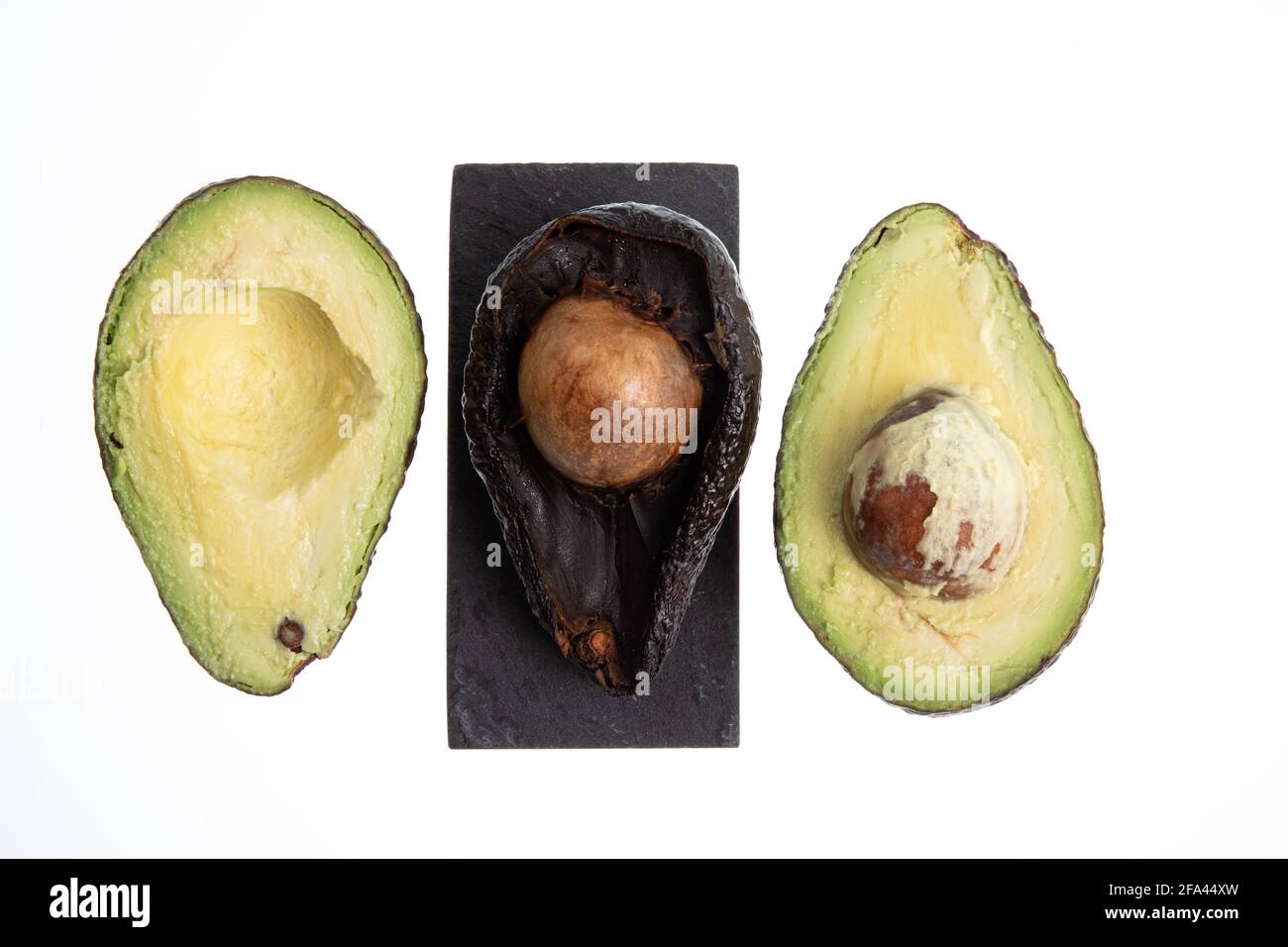Avocado fresco e maturo accanto all'avocado marcio tagliato in metà con  seme visibile isolato su bianco Foto stock - Alamy