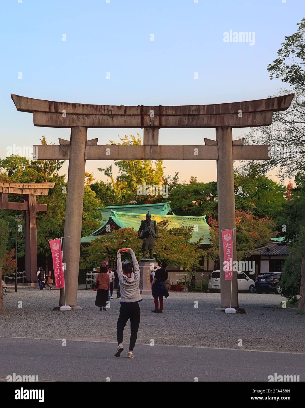 Osaka, Giappone - Ottobre 31 2020: Veduta pomeridiana di un pareggiatore che si estende di fronte al cancello torii all'entrata del Santuario Hokoku, con la statua di Foto Stock