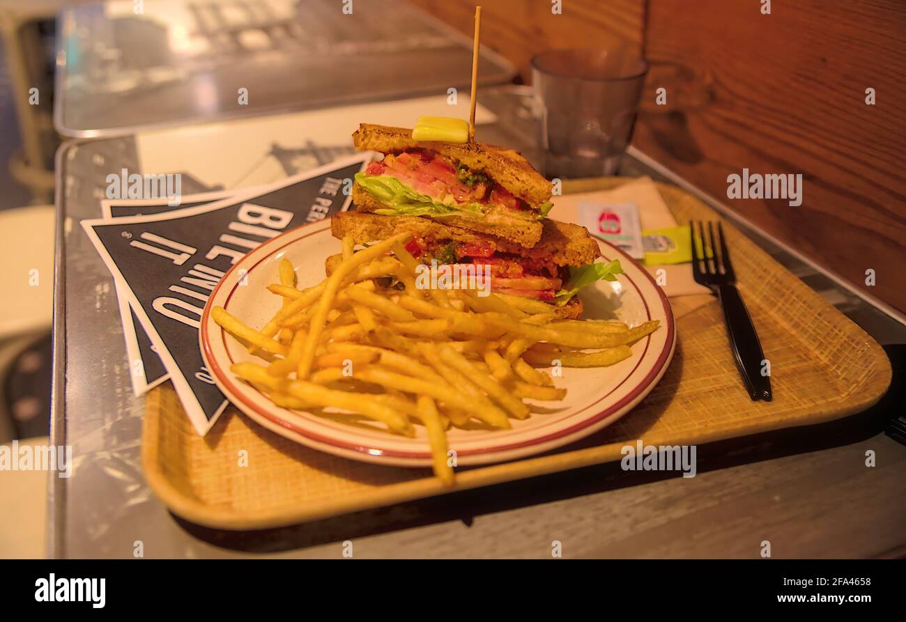Un panino gourmet BLT tostato con patatine fritte strarciate un tavolo in un ristorante Foto Stock