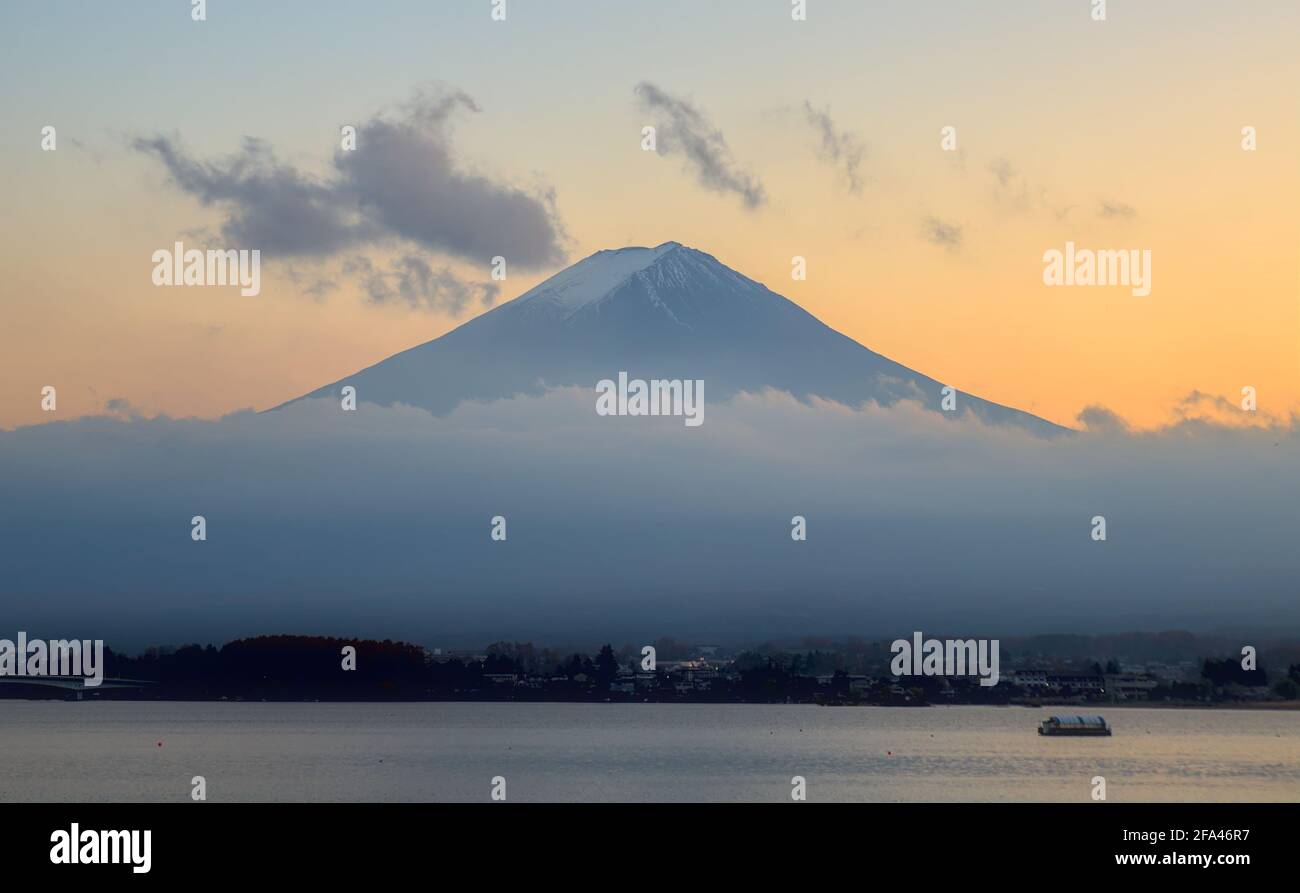 Nel tardo pomeriggio, vista di un Monte Fuji parzialmente protetto dalla nebbia e. Lago Kawaguchi sotto un cielo colorato tramonto Foto Stock