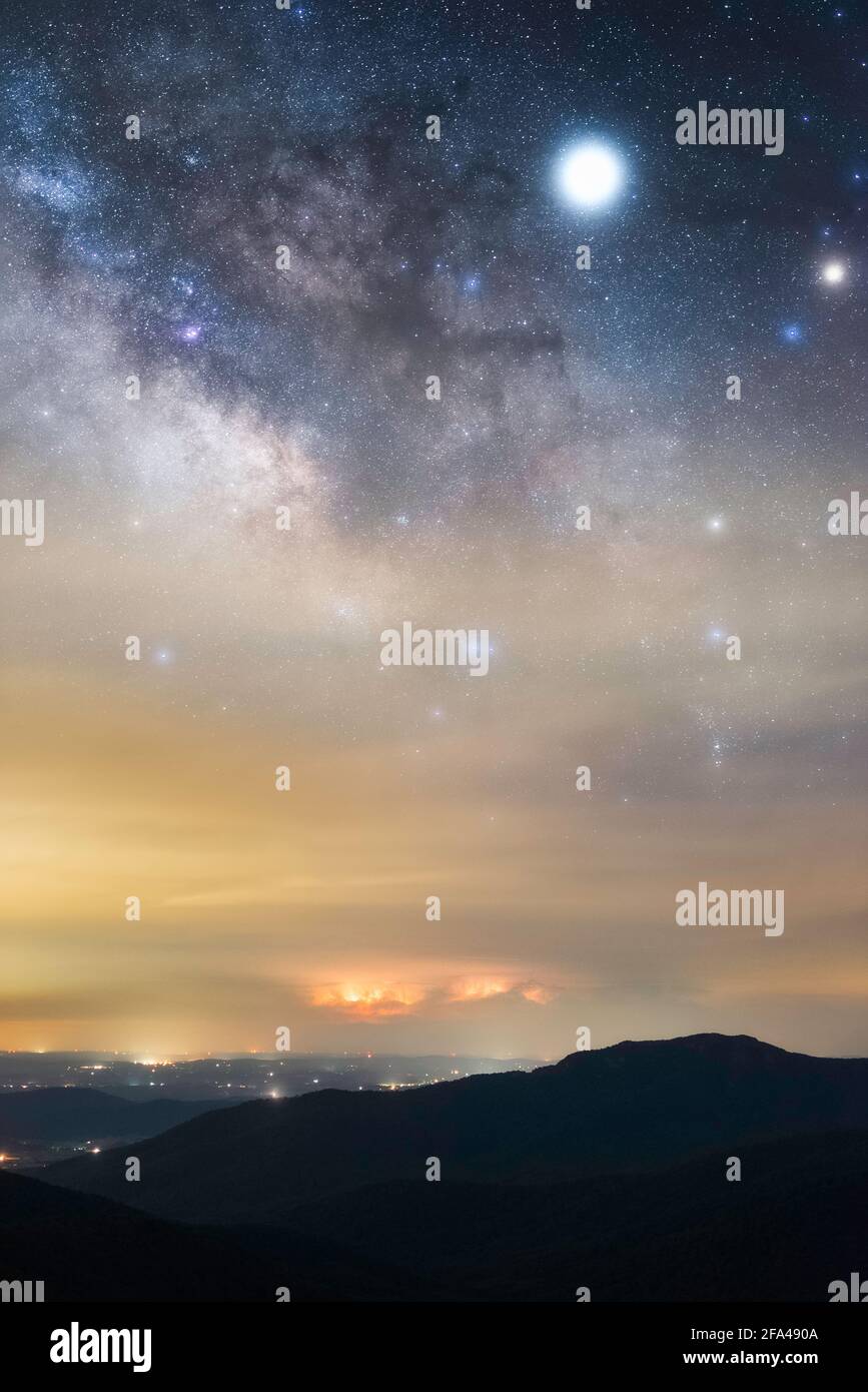 La Via Lattea che sorge su una lontana tempesta all'orizzonte con un fulmine rosso, vista dal Parco Nazionale di Shenandoah. Foto Stock