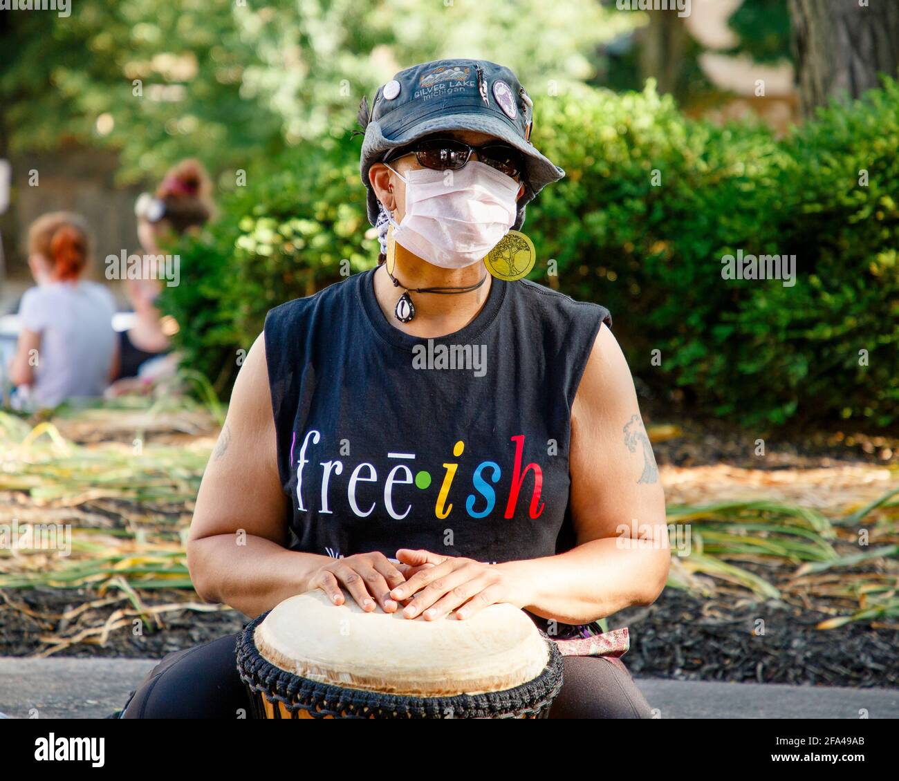 Una donna mascherata tamburi a una protesta per la giustizia razziale E diritti LGBTQ Foto Stock