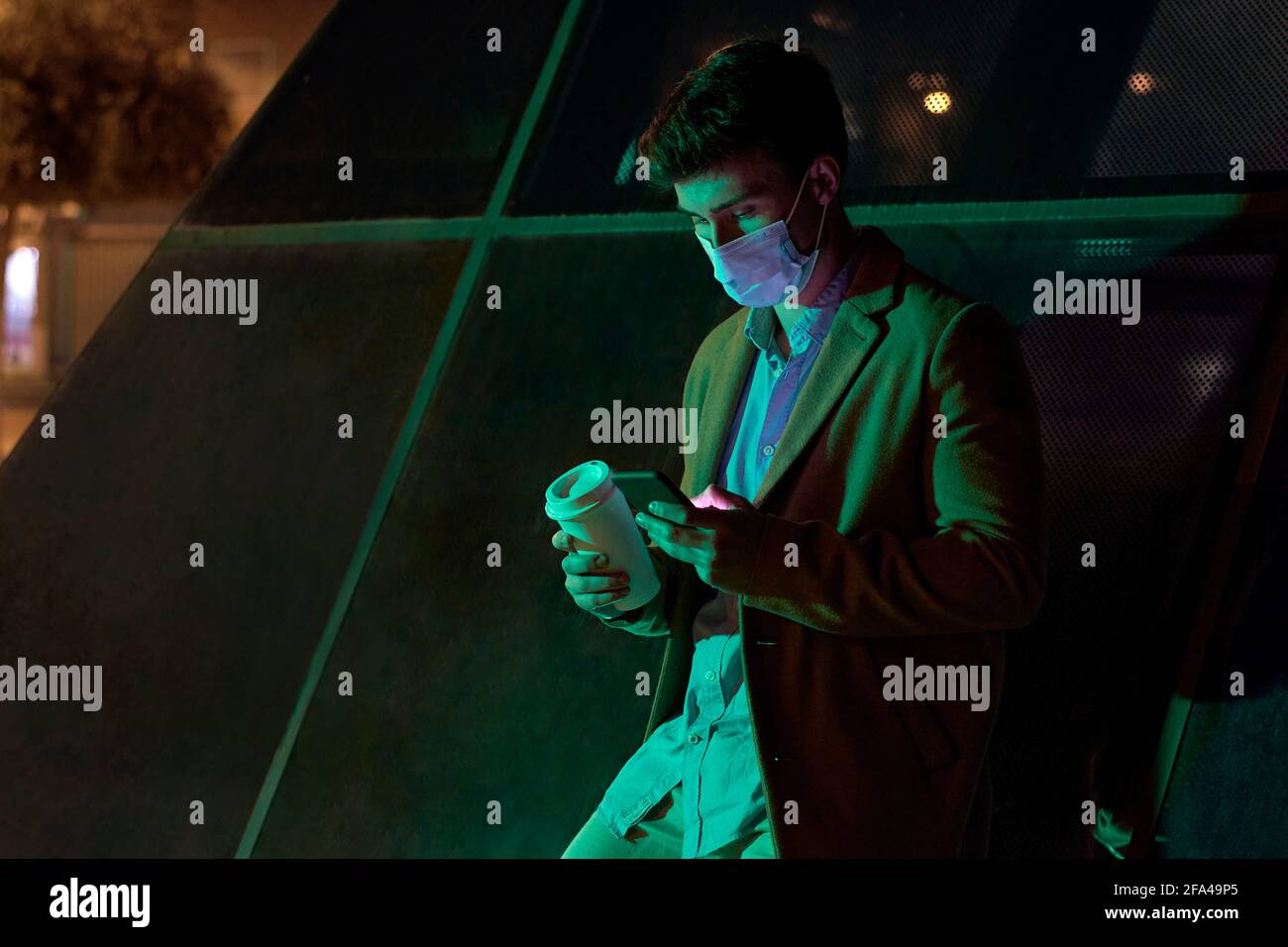 Giovane uomo d'affari con maschera illuminata dalle luci della città Foto Stock