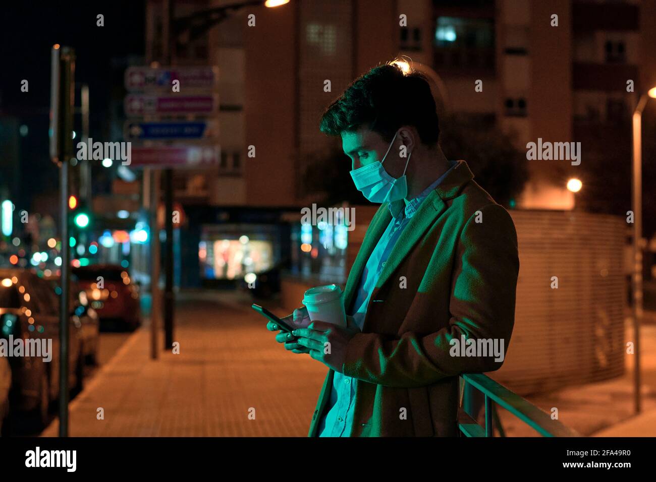 Giovane uomo d'affari con maschera illuminata dalle luci della città di notte Foto Stock