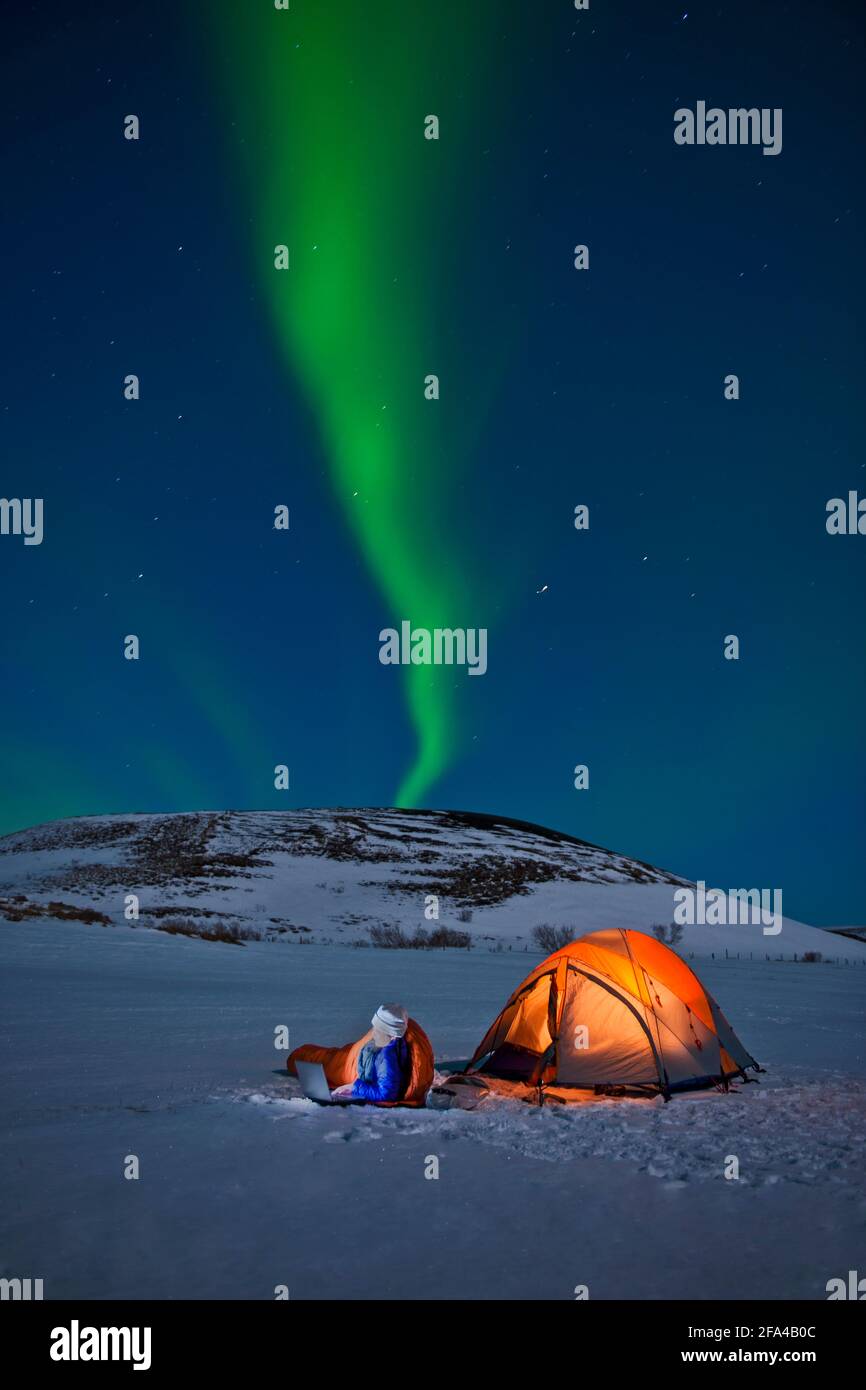 Lo scienziato siede fuori della sua tenda con l'aurora boreale dentro il cielo Foto Stock