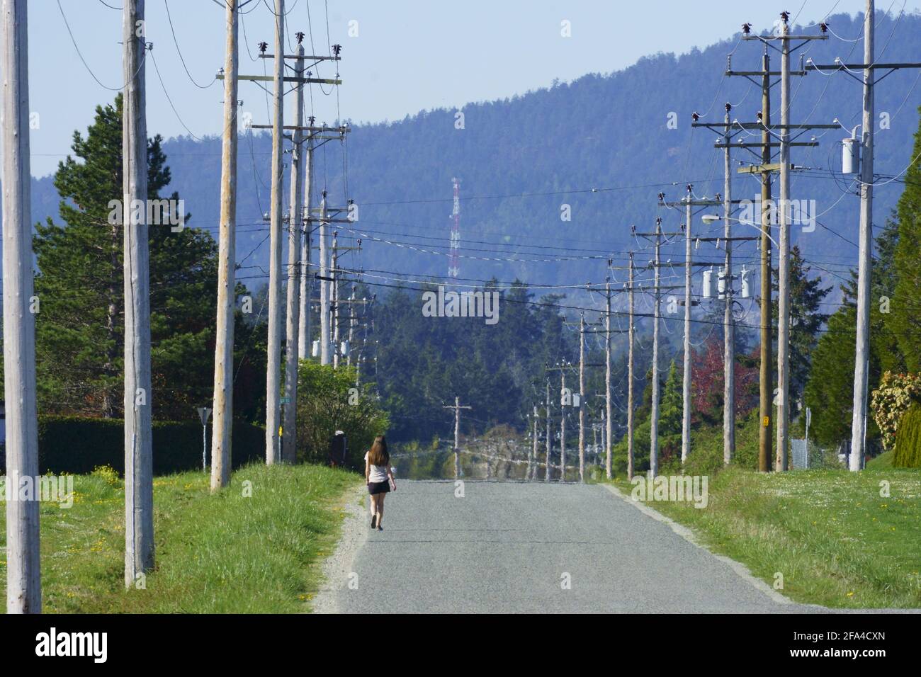Donna che cammina lungo la strada di campagna deserta Foto Stock