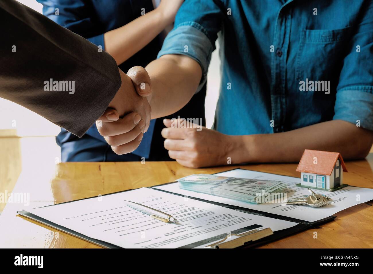 Sopra la vista della coppia sposata e del realtor amichevole scuotendo le mani dopo aver fatto affare immobiliare all'interno, sopra la vista. Foto Stock