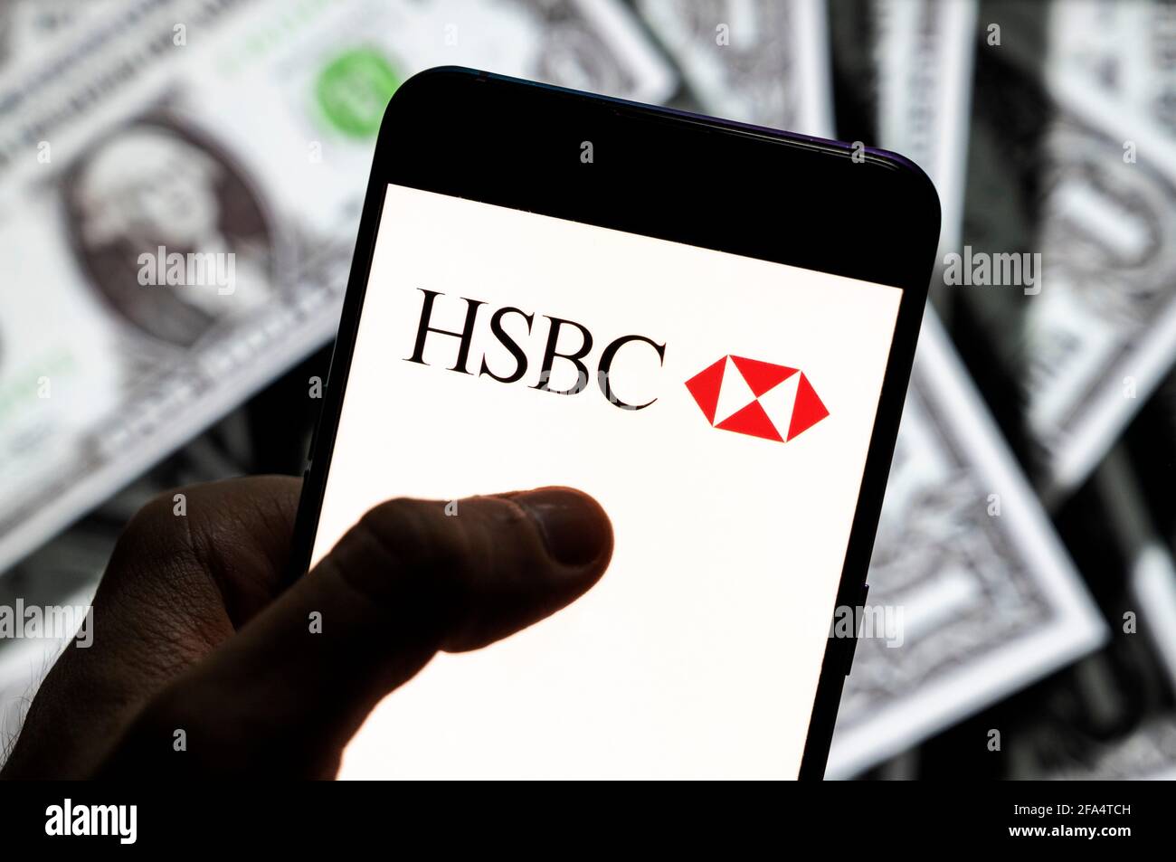 In questa illustrazione fotografica viene visualizzato il logo HSBC sullo schermo di un dispositivo mobile Android con la valuta dell'icona del dollaro statunitense e il simbolo dell'icona in dollari sullo sfondo. Foto Stock