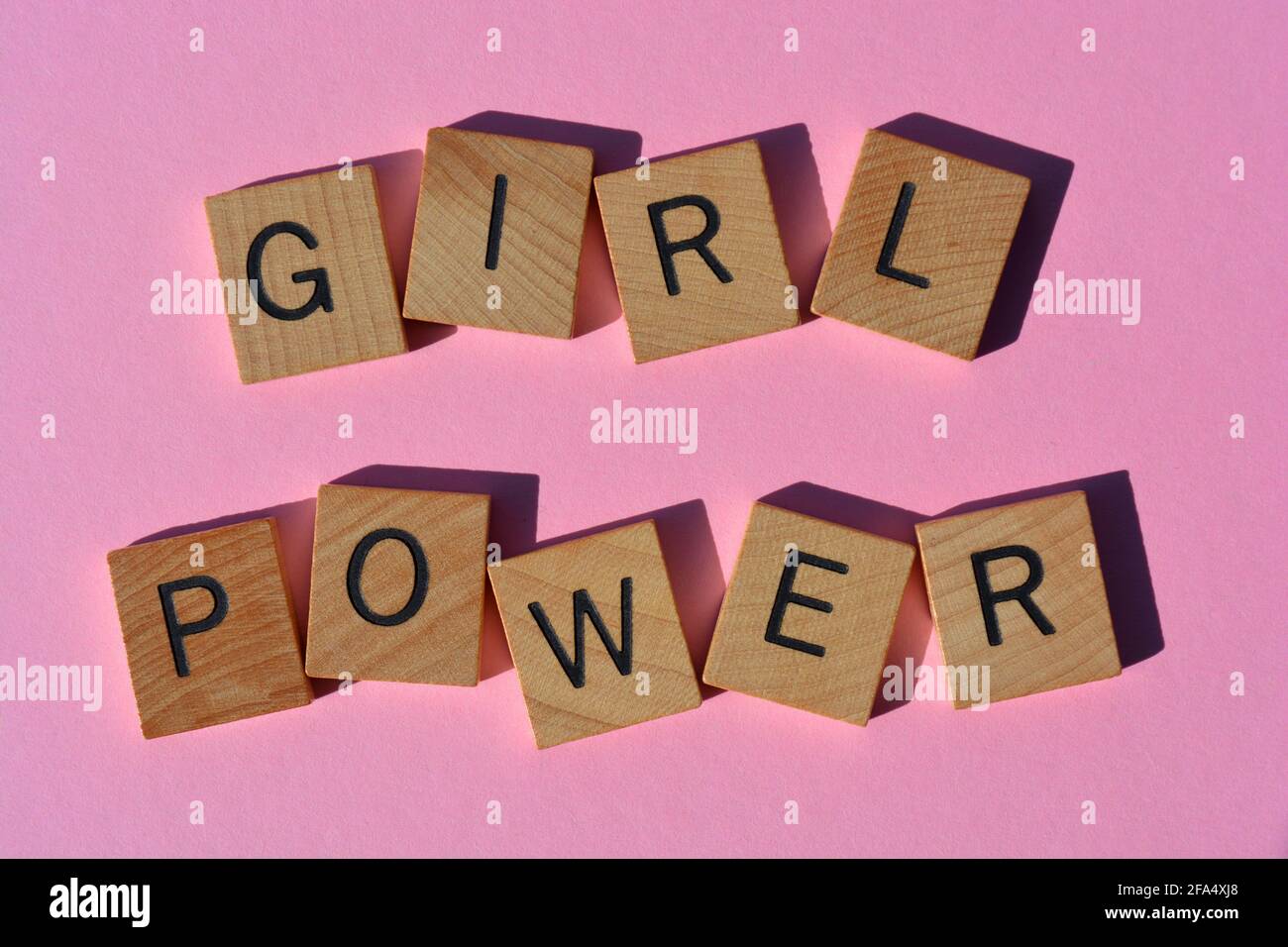 Girl Power, parole in lettere alfabetiche in legno isolate su sfondo rosa brillante Foto Stock