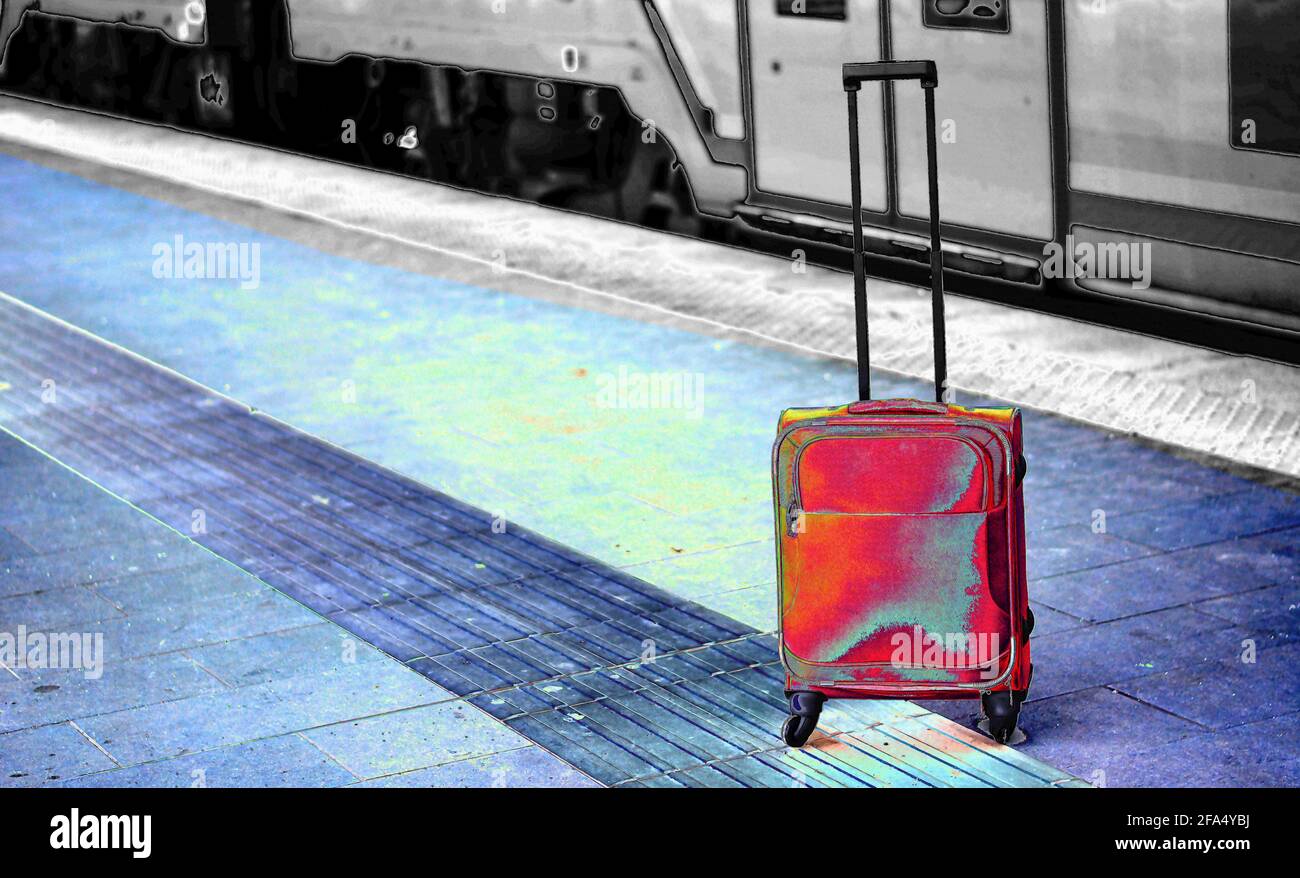 una valigia rossa alla stazione ferroviaria Foto Stock