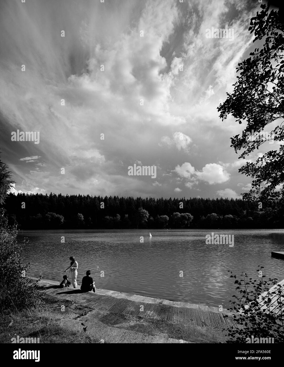 Bianco e nero di famiglia con yacht radiocontrollato a Shearwater Lake, Longleat, Crockerton, Warminster, Wiltshire, Inghilterra, Regno Unito Foto Stock