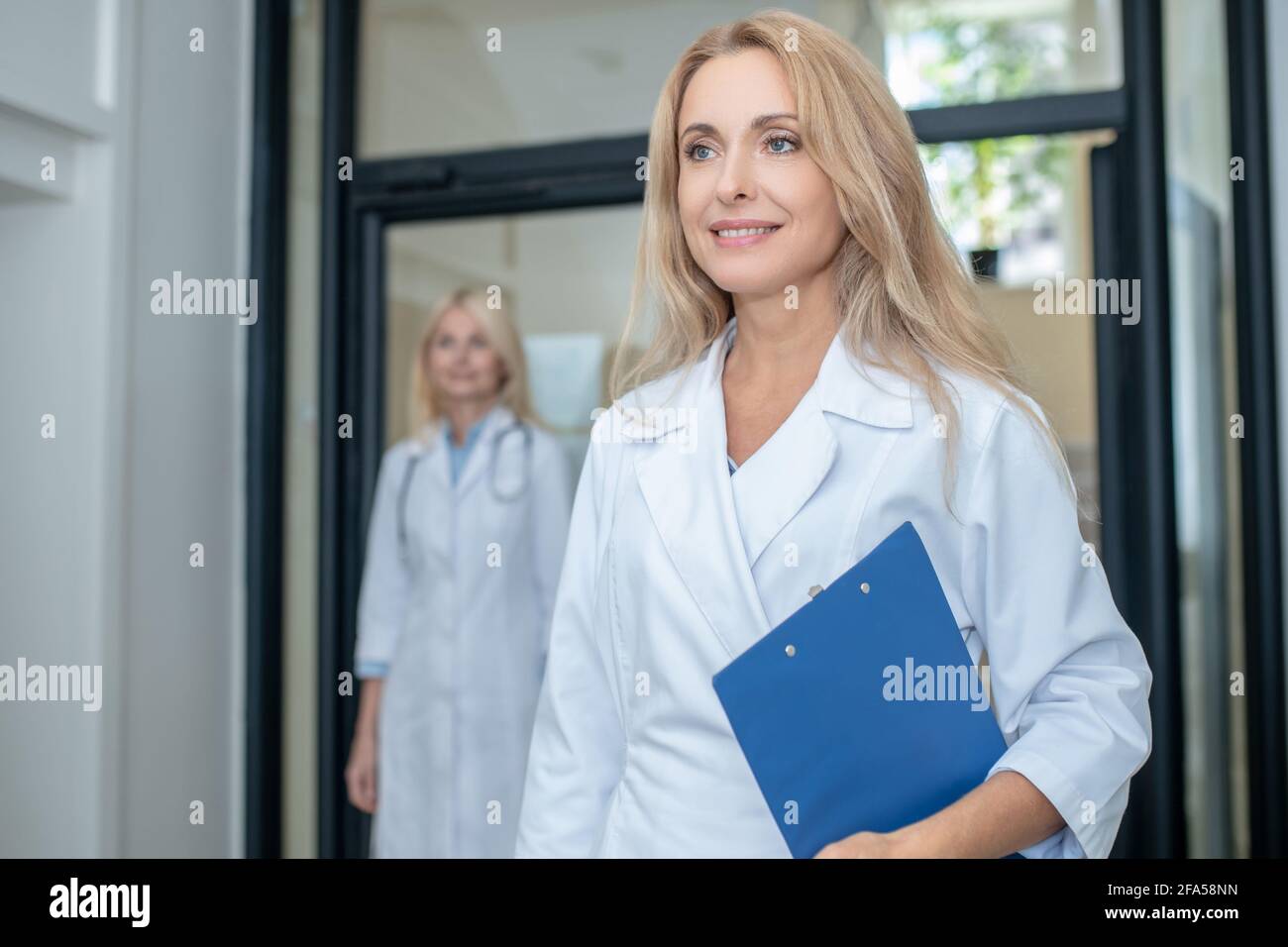 Donna felice in abito medico e collega Foto Stock