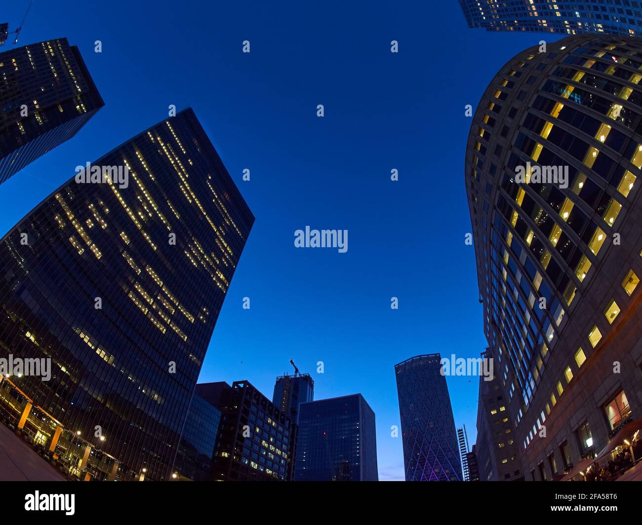 I grattacieli di Canary Wharf, vorticati e distorti da una lente fish-eye, sembrano apparire in alto contro un cielo crepuscolo. Foto Stock