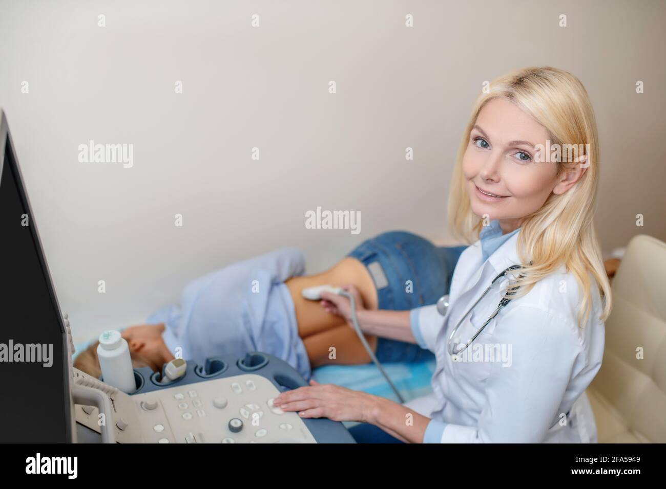 Medico che esegue l'esame ecografico e paziente sdraiato Foto Stock