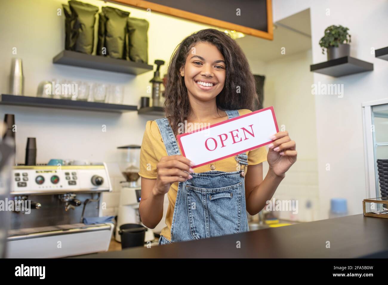 Donna al banco bar con un cartello che dice aperto Foto Stock