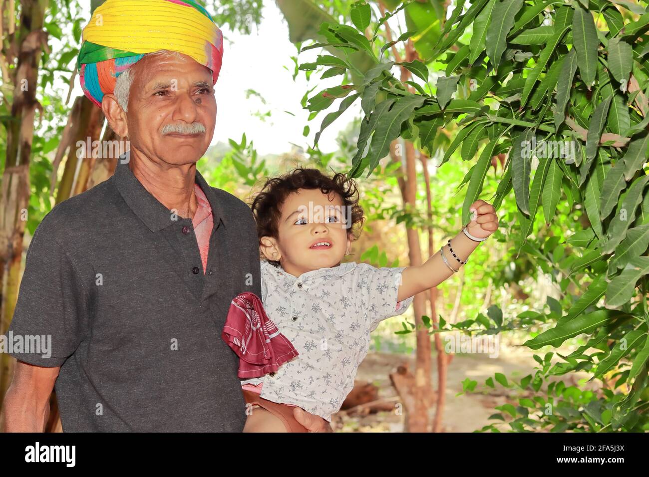 Primo piano ritratto di nonni anziani e nipoti di Indiani origine sorriso sulla vista di alberi verdi e piante nel giardino Foto Stock