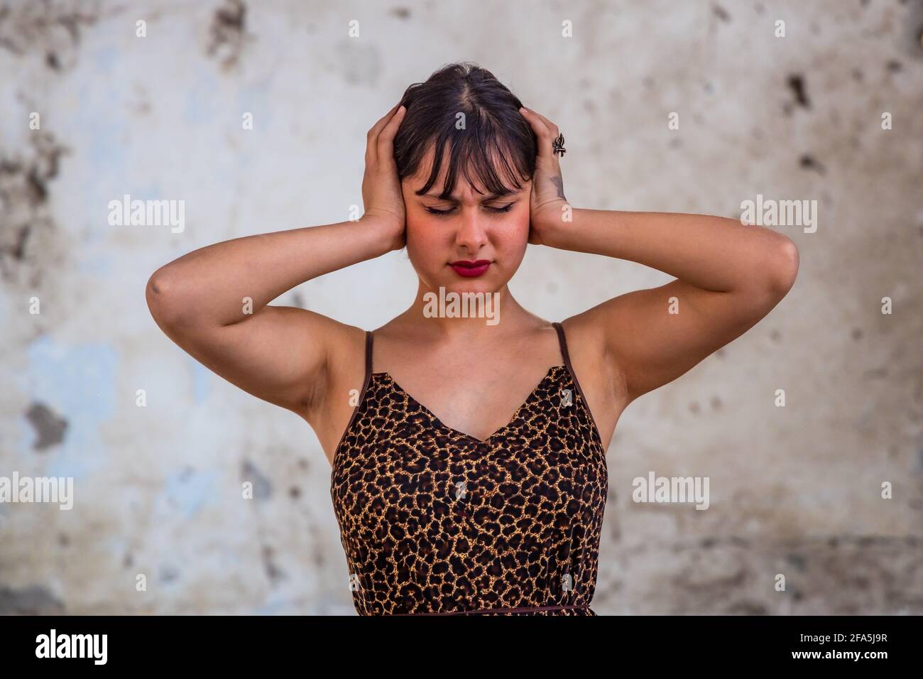 Ritratto di preoccupata bella donna bruna giovane stressata che soffre di emicrania, mani sulla testa che guardano verso il basso. Copia spazio, persone. Foto Stock