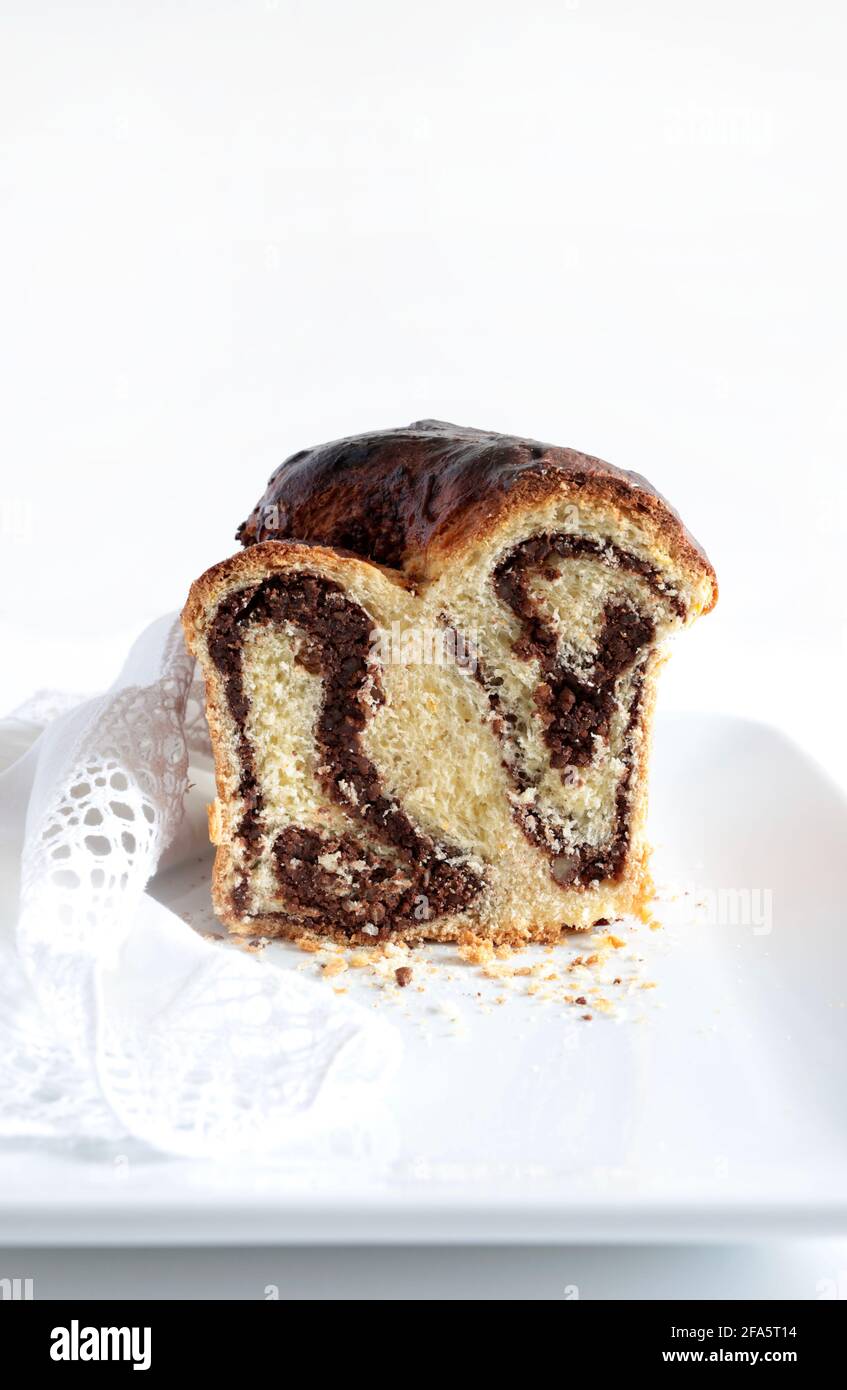 Pane dolce rumeno tradizionale fatto in casa chiamato 'cozonac', con cacao, uvetta e noci su sfondo bianco. Foto Stock