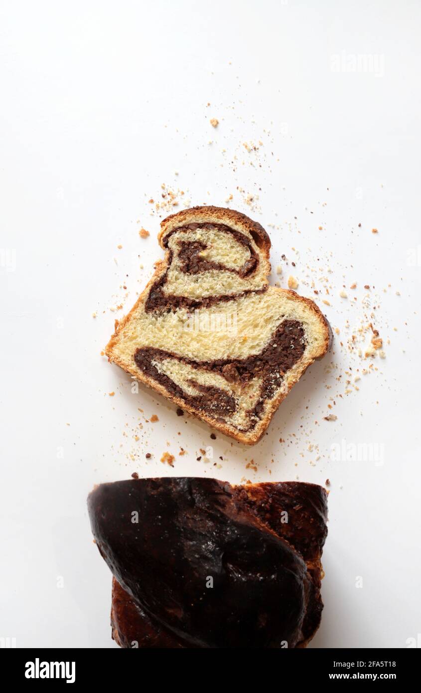 Pane dolce rumeno tradizionale fatto in casa chiamato 'cozonac', con cacao, uvetta e noci su sfondo bianco. Foto Stock