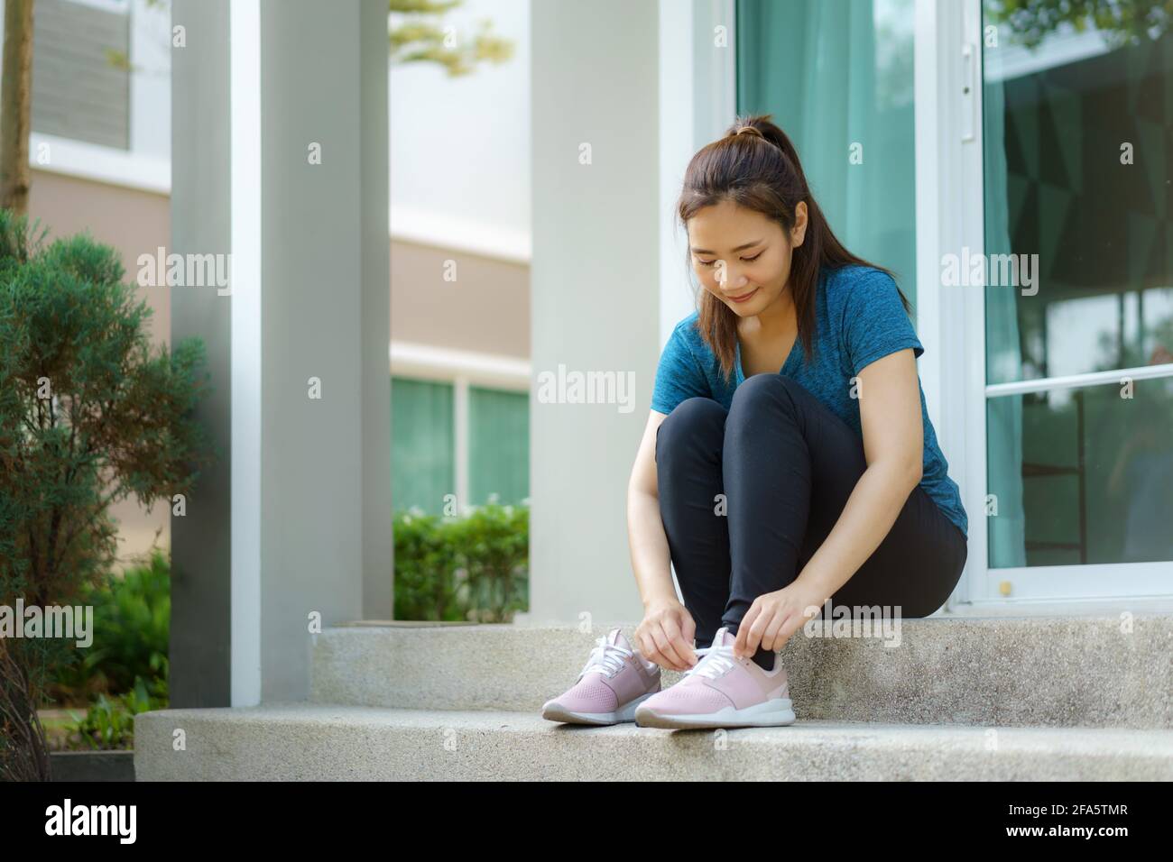 Le donne asiatiche indossano scarpe sui gradini anteriori delle loro case per fare jogging nel quartiere per la salute quotidiana e il benessere, sia fisico che di Foto Stock