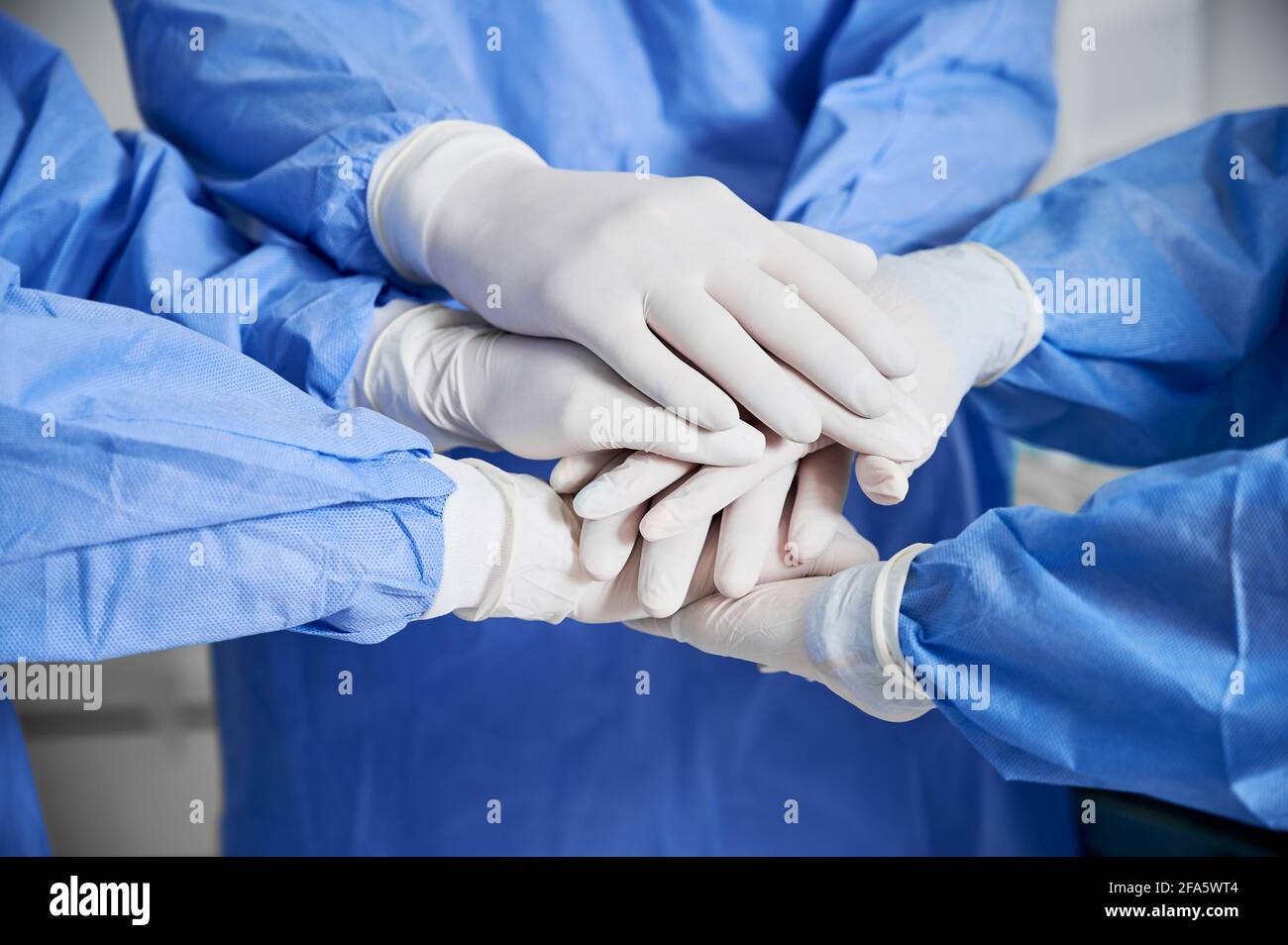 Primo piano degli operatori sanitari che uniscono le loro mani come simbolo di unità. Gruppo di medici con una pila di mani che indossano guanti sterili bianchi. Concetto di unità, lavoro di squadra e medicina. Foto Stock