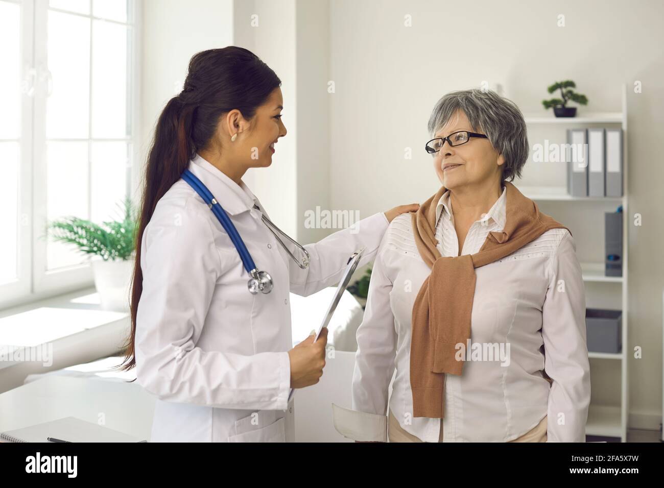 Paziente anziana di sesso femminile presso un medico professionista in clinica moderna Foto Stock