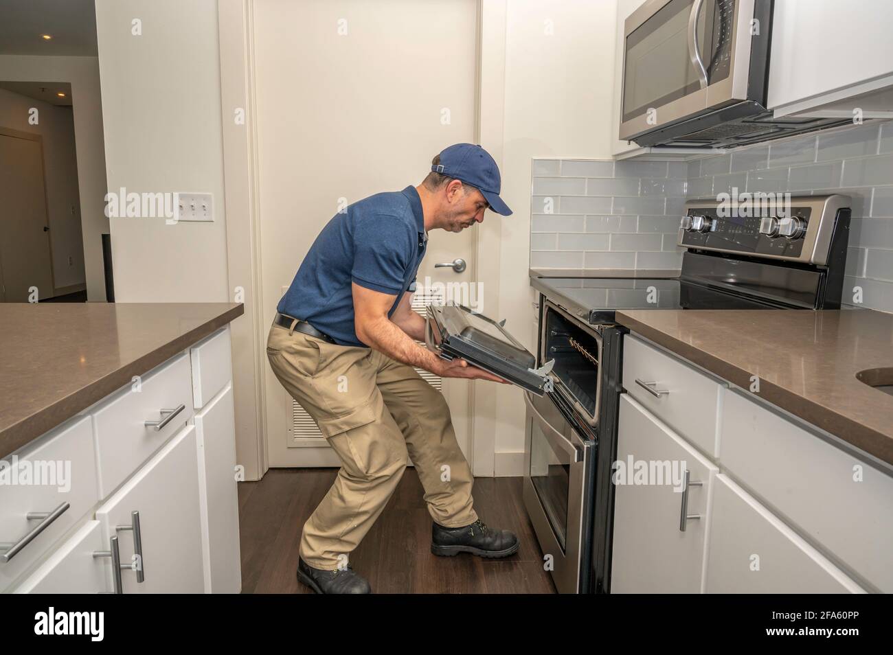 Tecnico dell'apparecchio rimozione di uno sportello del forno per la riparazione in un casa Foto Stock