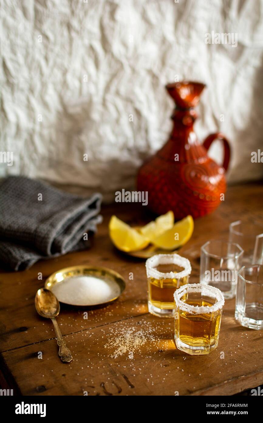 Alcuni bicchieri di tequila con un brim di sale e fette di limone su un tavolo di legno vecchio stile vintage in un bar. Foto Stock
