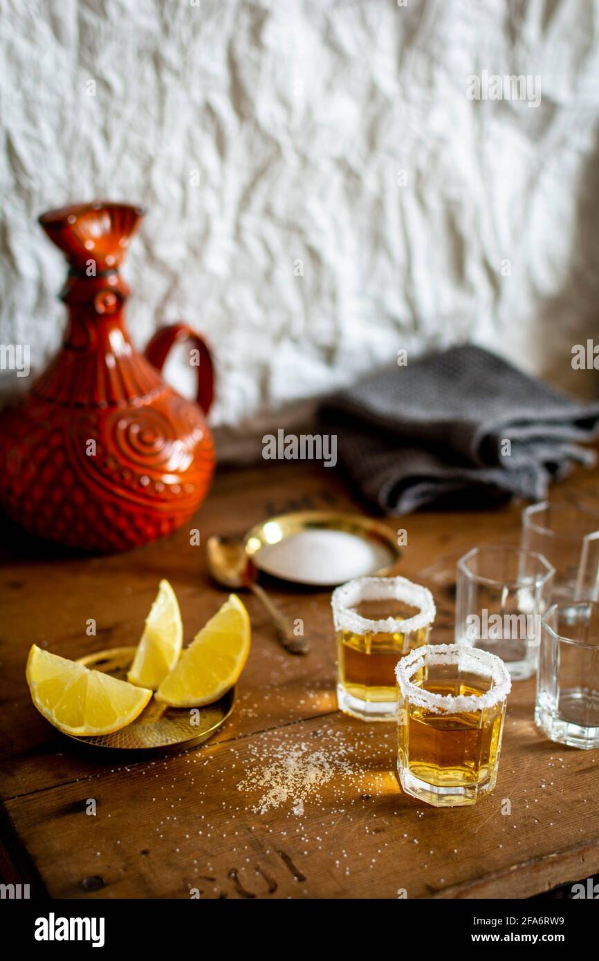 Alcuni bicchieri di tequila con un brim di sale e fette di limone su un tavolo di legno vecchio stile vintage in un bar. Foto Stock