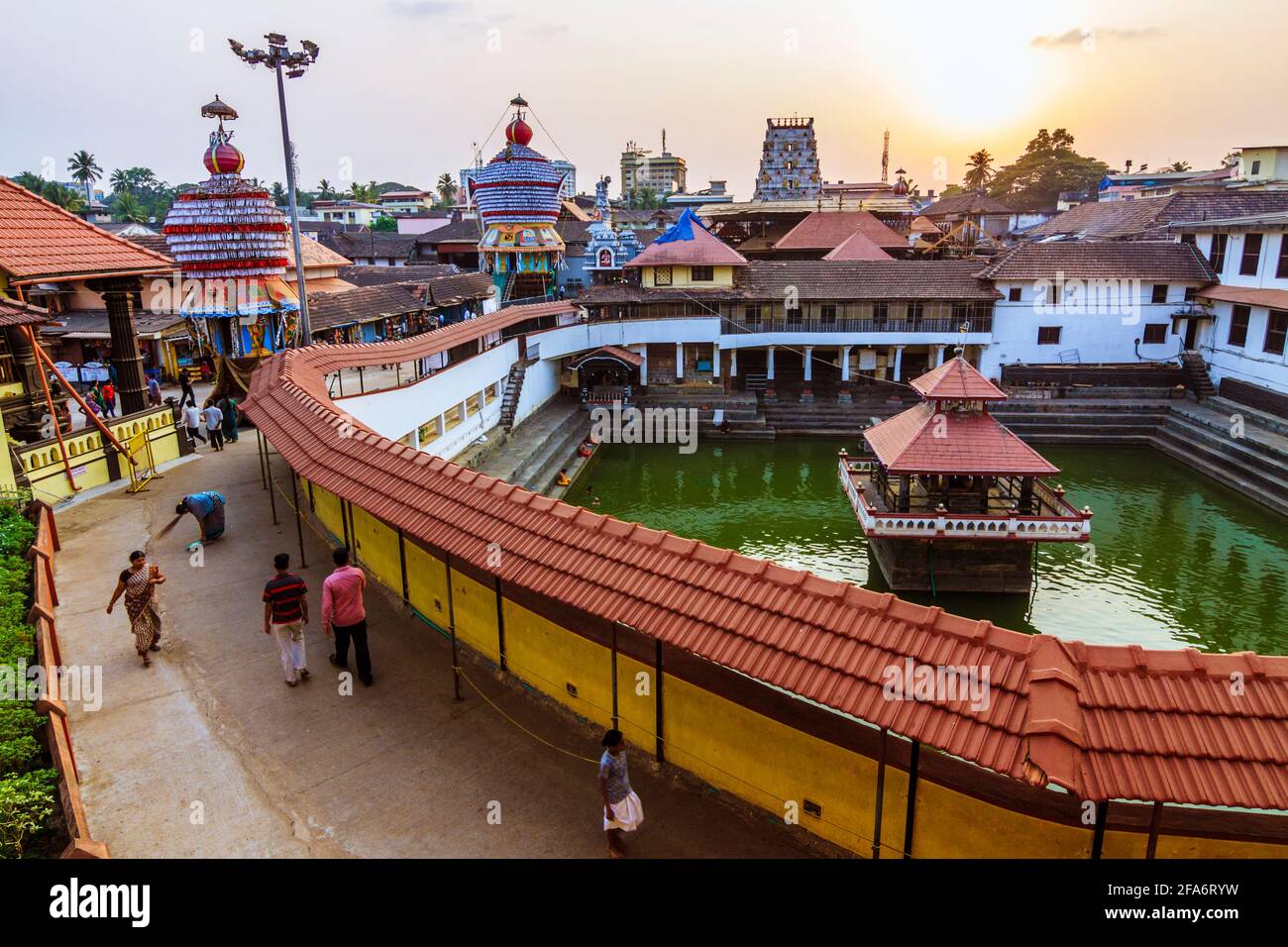 Udupi, Karnataka, India : la gente cammina al tramonto intorno al serbatoio d'acqua di Madhva Sarovara adiacente al tempio di Krishna 13 ° secolo fondato dal locale Foto Stock