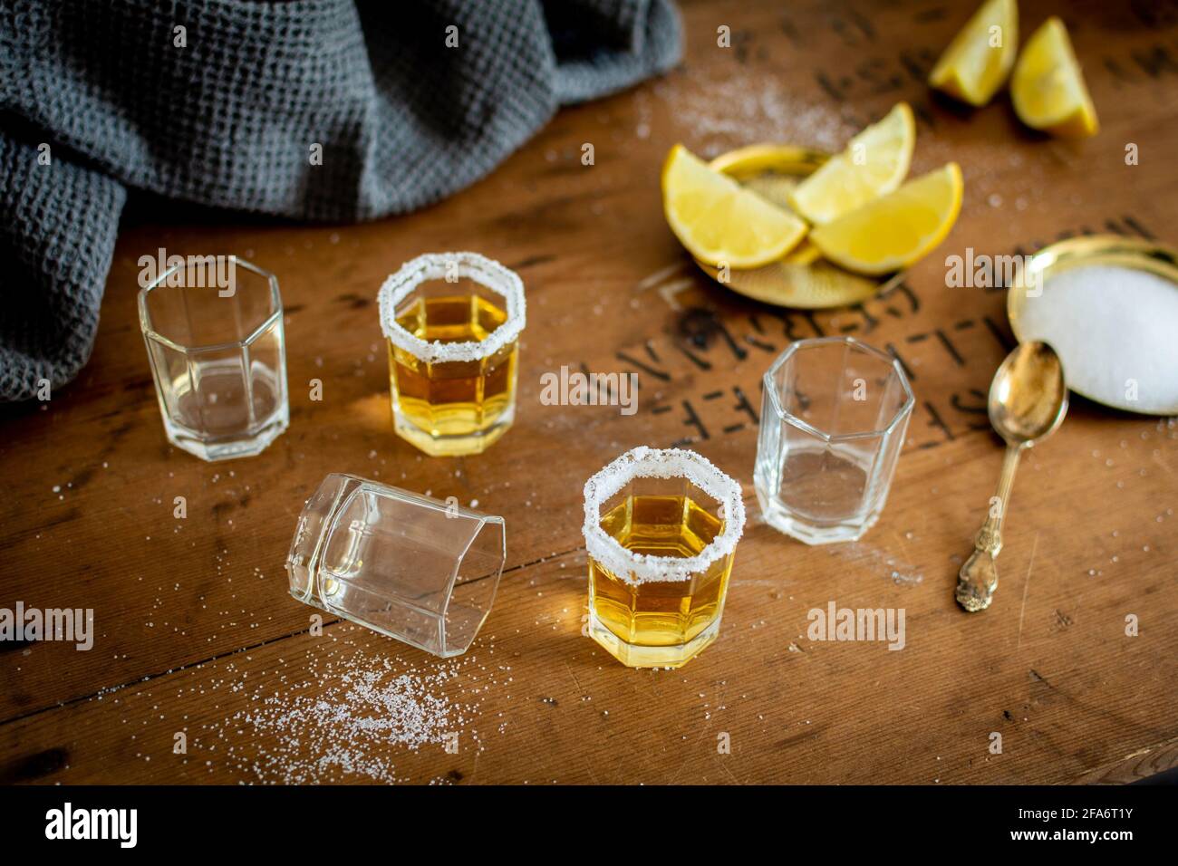 Alcuni bicchieri di tequila con un brim di sale e fette di limone su un tavolo di legno vecchio stile vintage in un bar. Foto Stock