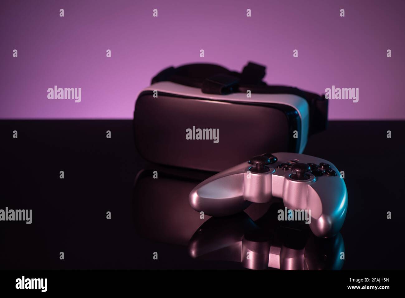 Joystick e visore VR su sfondo viola scuro Foto Stock