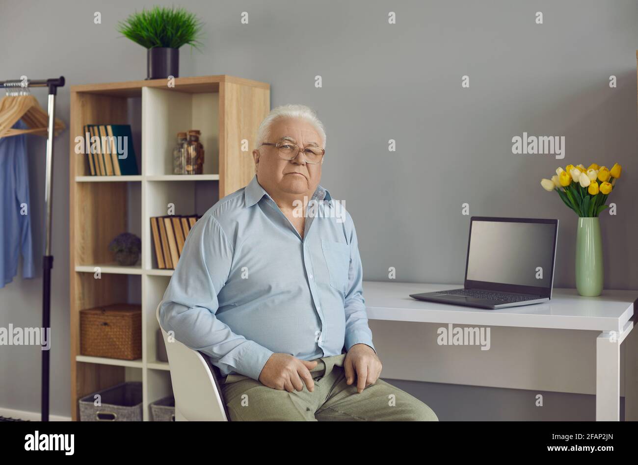 Vecchio uomo caucasico anziano al tavolo seduto al tavolo camera per ufficio a casa Foto Stock