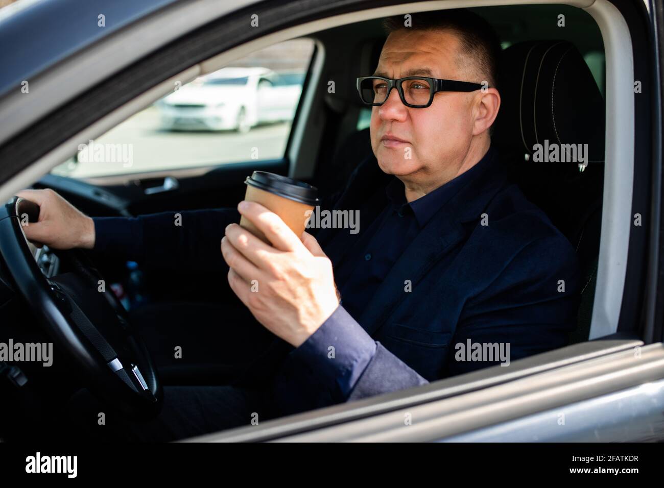 L'uomo di mezza età sperimenta un'auto intelligente con guida autonoma e ha un tazza di caffè Foto Stock