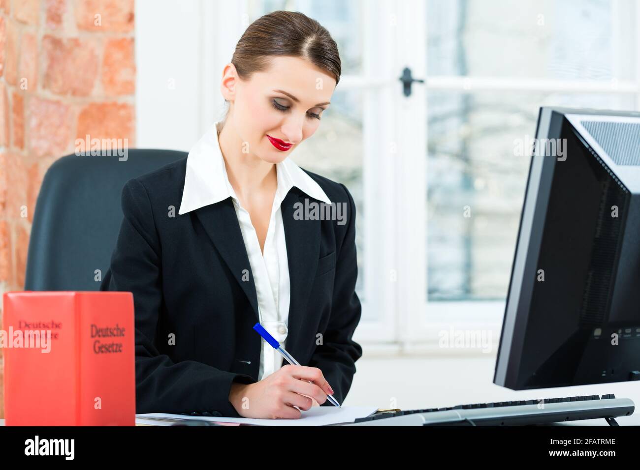 Giovane avvocato lavorando nel suo ufficio, lei è seduta dietro le cartelle la scrittura in un file Foto Stock