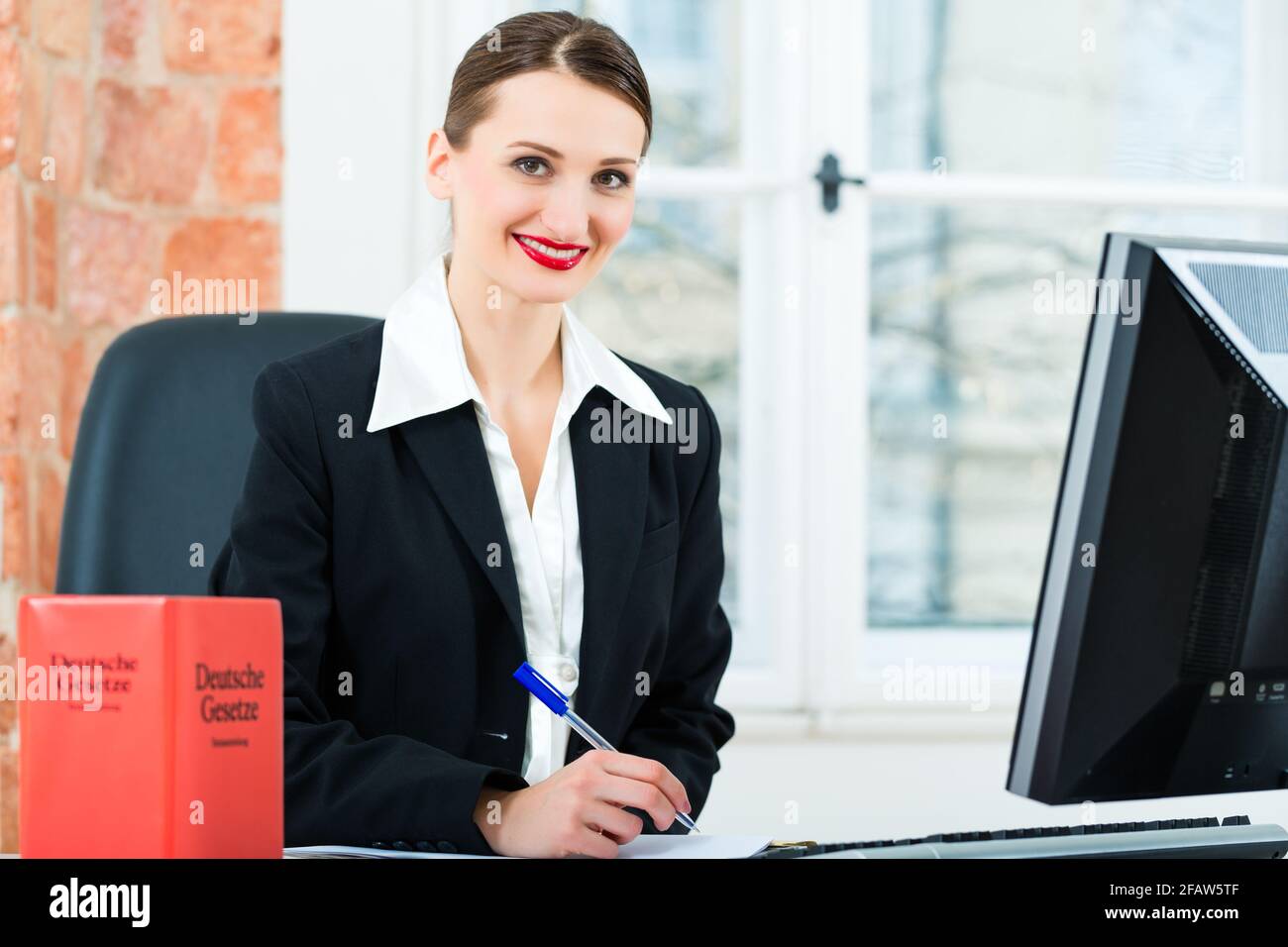Giovane avvocato lavorando nel suo ufficio, lei è seduta dietro le cartelle la scrittura in un file Foto Stock