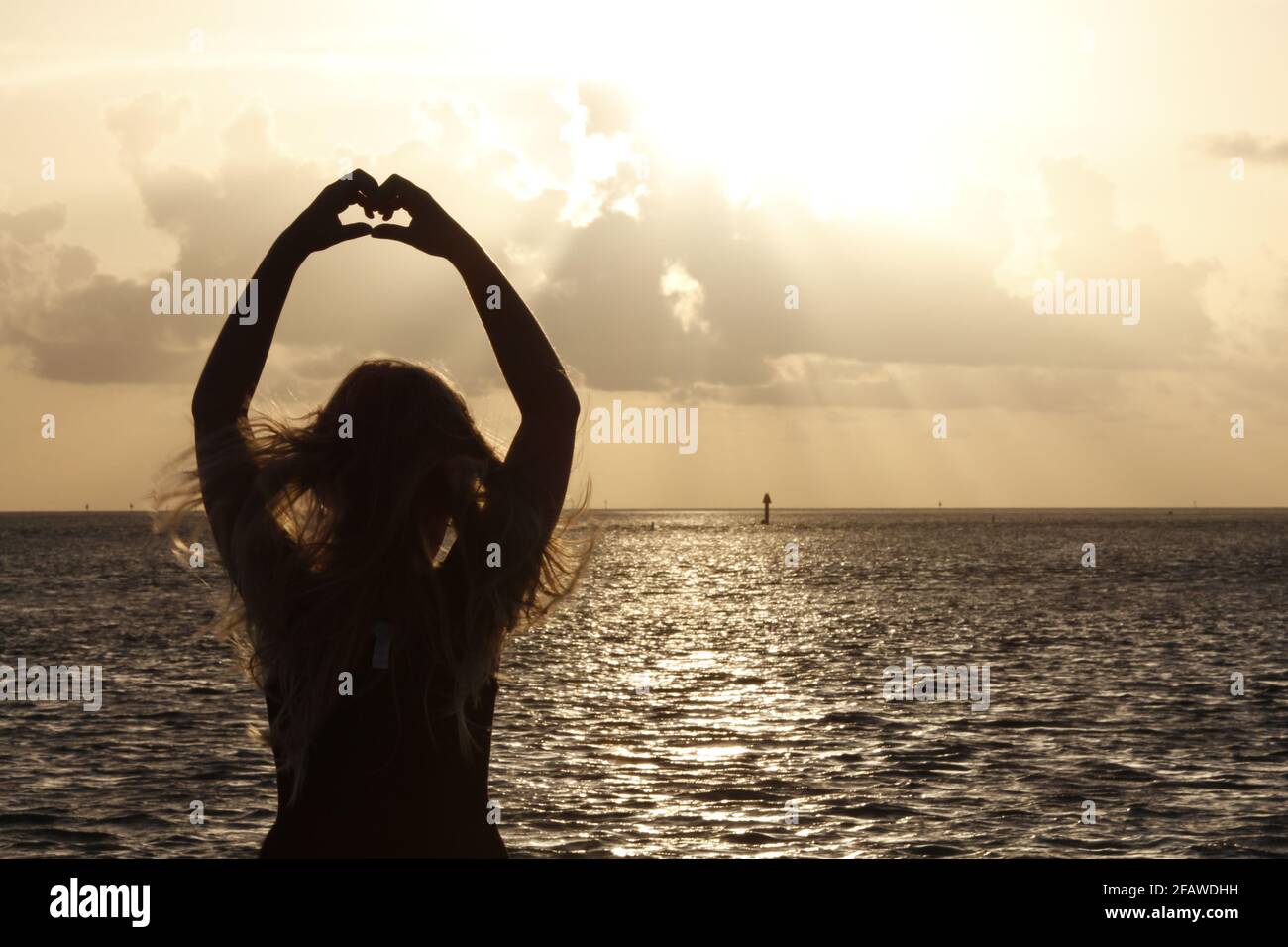 Giovane ragazza che crea una forma di calore all'alba Foto Stock