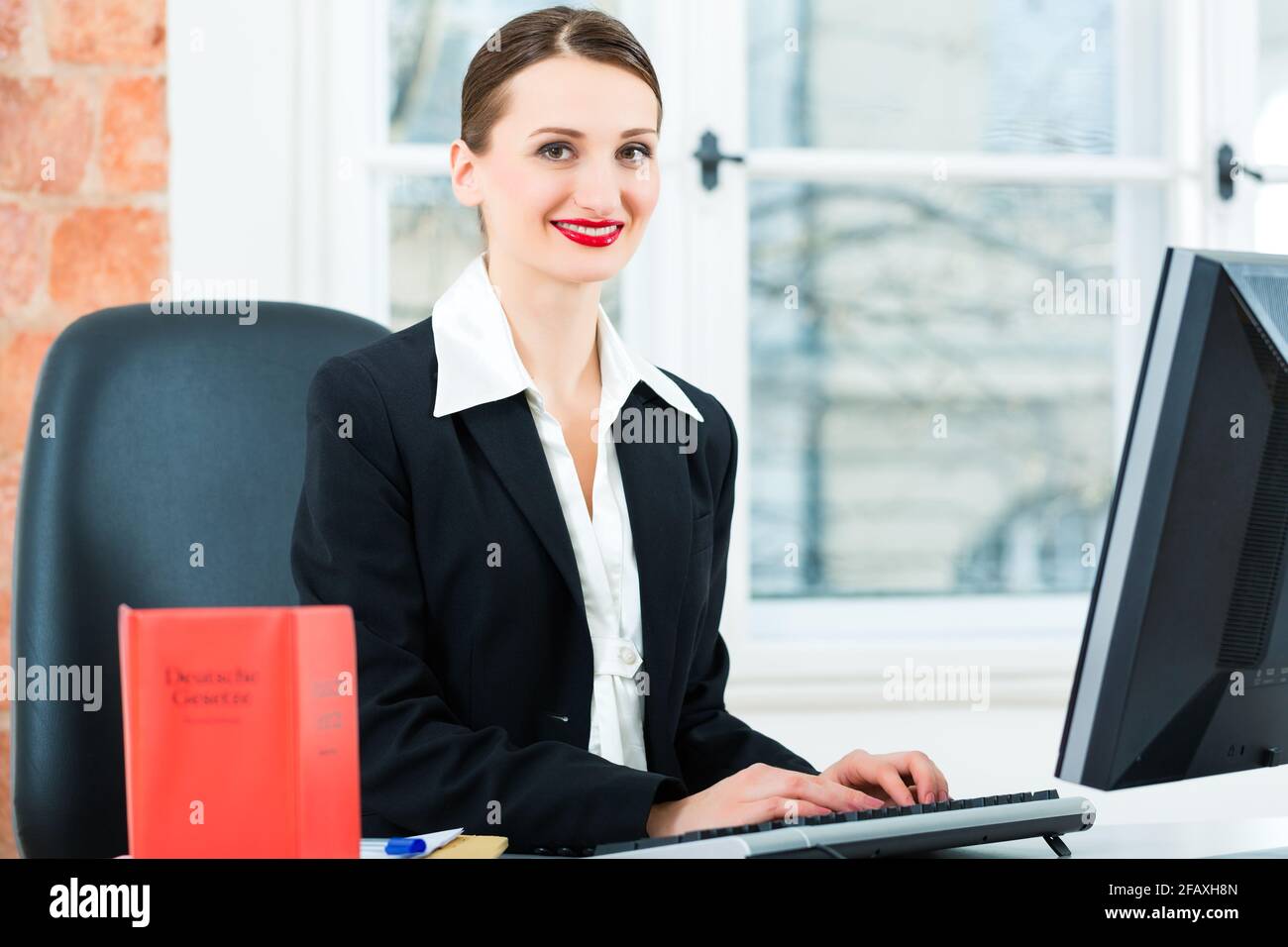 Giovane avvocato lavorando nel suo ufficio, lei è seduta dietro le cartelle la scrittura in un file Foto Stock