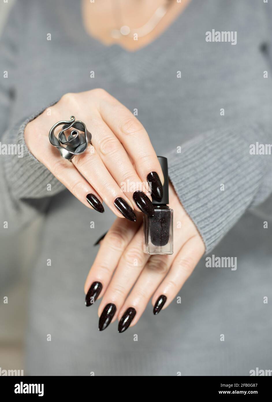 Mani donna con unghie lunghe e manicure nera con bottiglie di smalto per  unghie Foto stock - Alamy