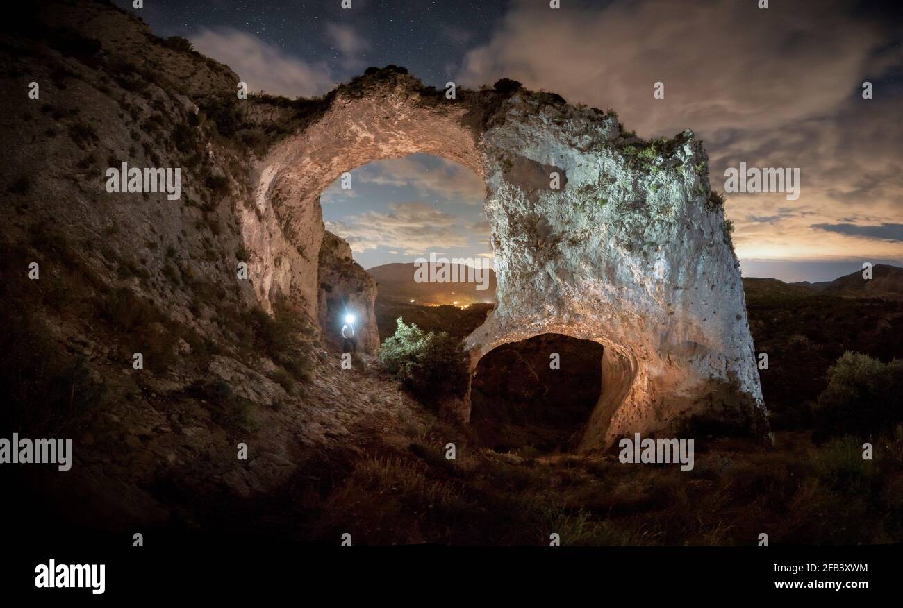 La silhouette di un uomo illumina due grandi archi in pietra Foto Stock