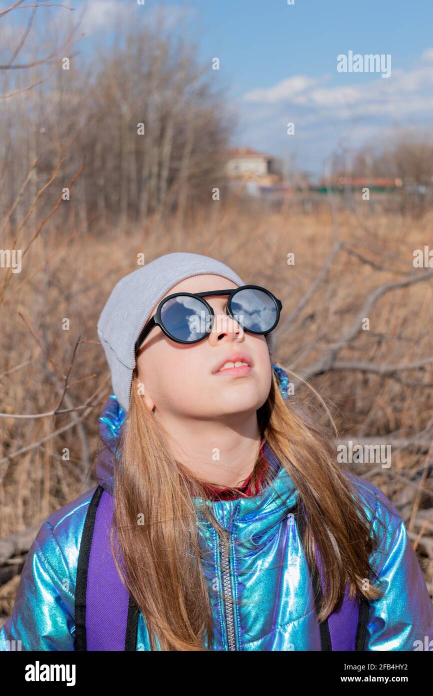 Adolescente ragazza in occhiali da sole specchiati guarda nel cielo. Concetto di benessere Foto Stock