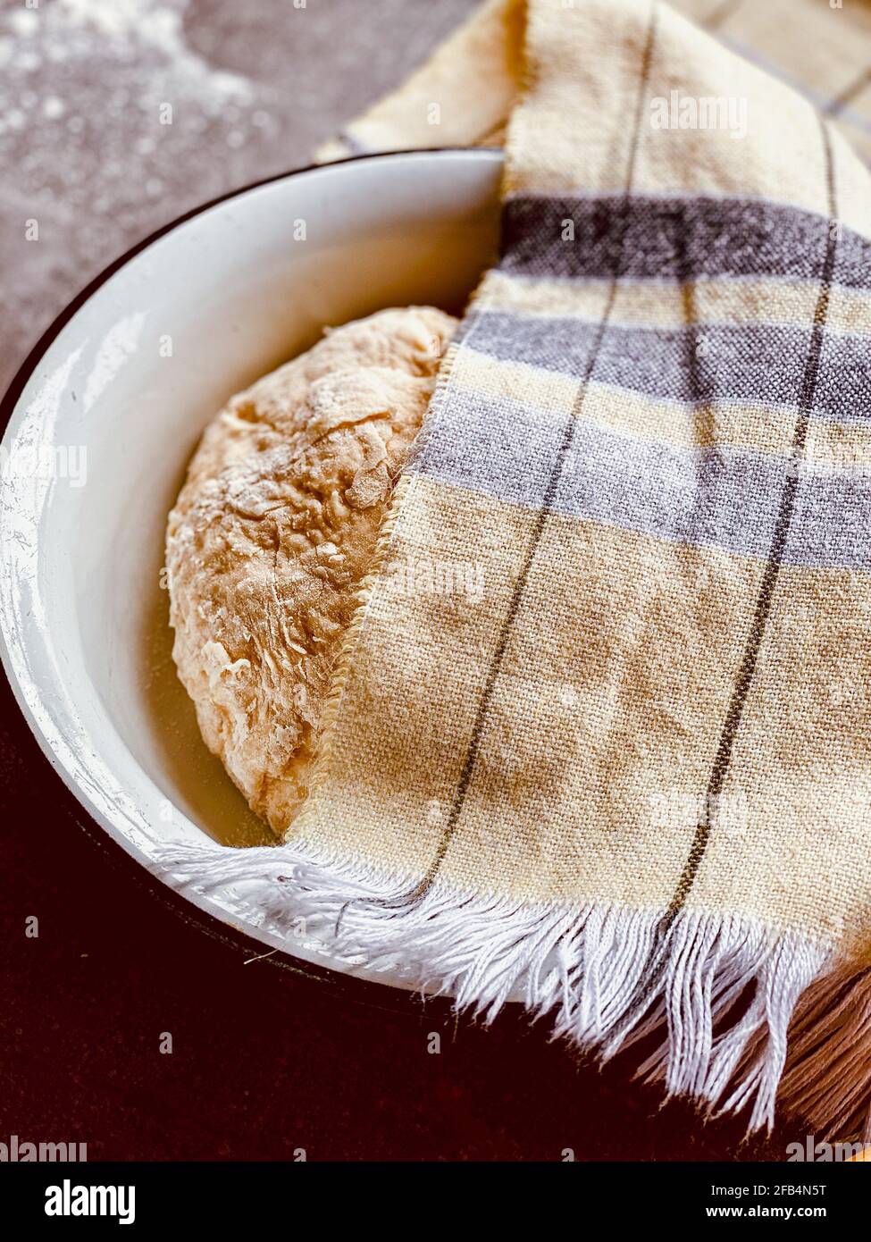 impastare in una ciotola sotto un tovagliolo Foto Stock