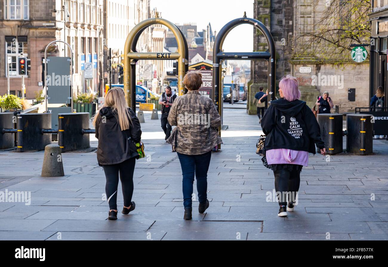 Tre donne compongono artisti che camminano sulla parte di Royal Mile della troupe cinematografica durante le riprese a Edimburgo, Scozia, Regno Unito Foto Stock